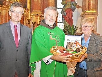 Pfarrgemeinderatsvorsitzender Michael Gärtlein (links) und Kirchenpfleger Karlheinz Kohles überreichten Pater Rufus Witt einen Korb mit fränkischen Spezialitäten. Foto: Ingrid Kohles