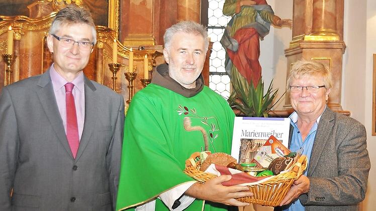 Pfarrgemeinderatsvorsitzender Michael Gärtlein (links) und Kirchenpfleger Karlheinz Kohles überreichten Pater Rufus Witt einen Korb mit fränkischen Spezialitäten. Foto: Ingrid Kohles