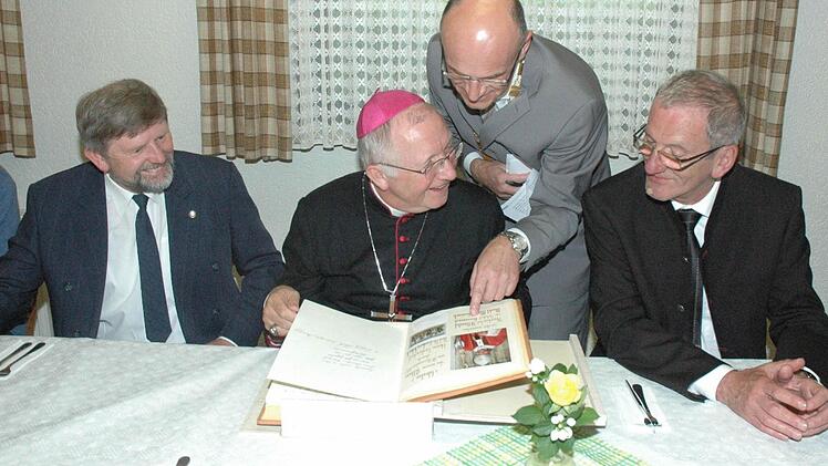 Weihbischof Ulrich Boom muss lachen, als er einen seiner Vorgänger Helmut Bauer im Goldenen Buch des Marktes Maroldsweisach findet. Bürgermeister Wilhelm Schneider (Mitte) erklärt dem Bischof die Einträge, während Pfarrer Richard Brütting (links) und Dr. Jürgen Lenssen (rechts) amüsiert zuschauen. Foto: Schmidt