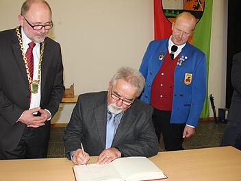 Hans Elflein trägt sich ins Gästebuch ein, beobachtet von Bürgermeister Robert Herrmann (links) und Theo Lerche (rechts. Foto: Ralf Kestel