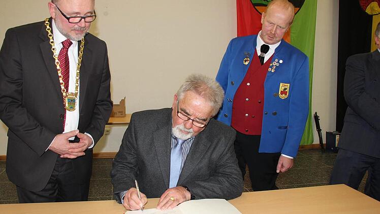 Hans Elflein trägt sich ins Gästebuch ein, beobachtet von Bürgermeister Robert Herrmann (links) und Theo Lerche (rechts. Foto: Ralf Kestel
