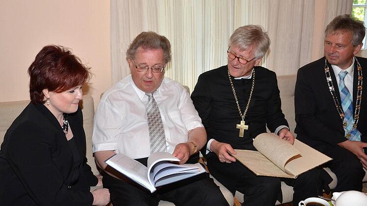 ...während Pfarrer Ahrens das Buch von Roland Lutz in Händen hält. Christina Flauder und Bürgermeister Diersch schauen zu.