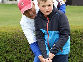 Hans Kämpf zeigt den Kindern das Putten - also das Einlochen. Hier übt er mit Felix die richtige Schlägerhaltung. Foto: Müller-Sanke