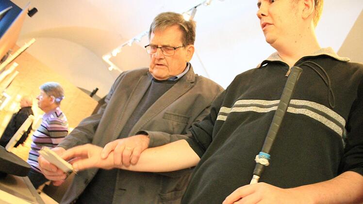 Horst Rüdel führt die Hand eines Teilnehmers der Führung für Sehbehinderte behutsam über einen Teil eines Holzmodells. Foto: Dominic Buckreus