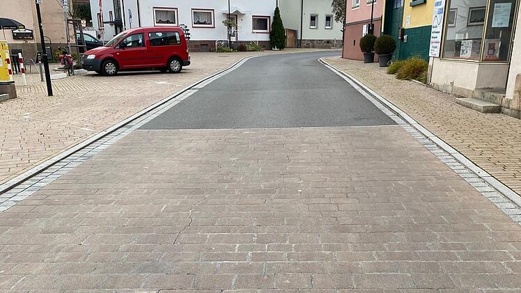 Das Bild zeigt eine der Flächen am Marktplatz, bei denen das Pflaster entfernt und durch hellen Asphalt ersetzt wird. Dadurch sollen die Abrollgeräusche der Fahrzeuge minimiert werden. Foto: Thomas Kirchner/Markt Oberthulba