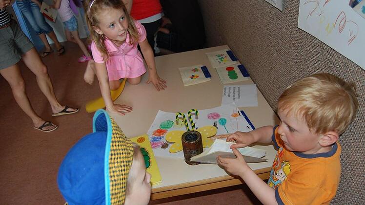Liliane und der kleine Felix zeigen ihr Bilderbuch über das Geschehen mit der Raupe.