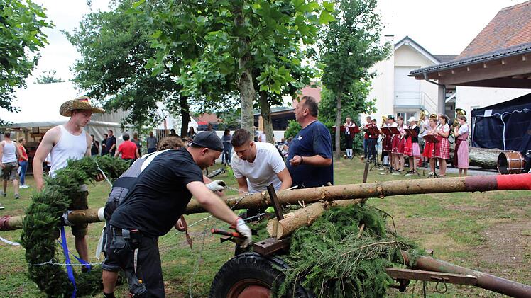 Der Baum wird bekränzt. Im Hintergrund die Blaskapelle Zentbechhofen.