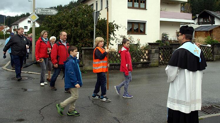 Pfarrer Richard Reis (rechts) begrüßt die Wallfahrer aus Nurn mit Weihwasser. Foto: Susanne Deuerling
