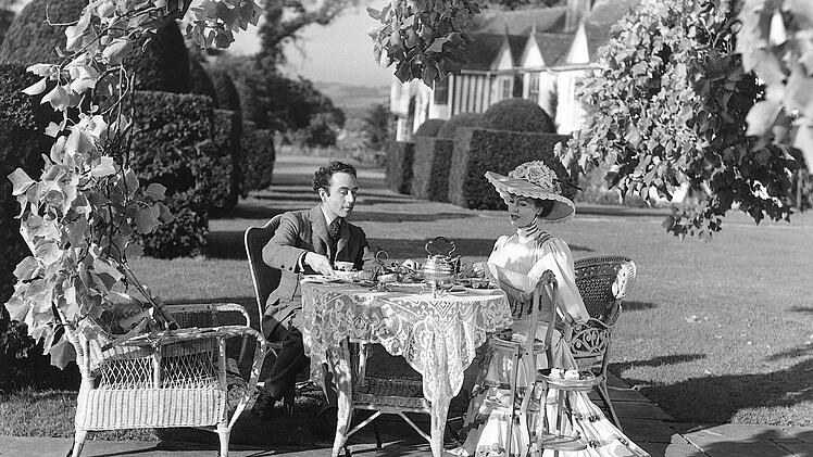 Seelenruhig sitzen Louis Mazzini (Dennis Price) und Edith D'Ascoyne (Valerie Hobson) f&uuml;r eine Teezeit beisammen. Edith ahnt nicht, welches Schicksal ihren Ehemann Henry bald ereilen wird.