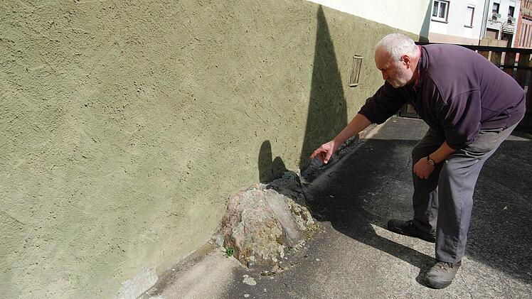 Viele Häuser im Ort stehen auf Sandsteinfelsen: Willi Wehner an seinem Haussockel, wo einer der Felsblöcke hervorschaut.  Foto: Günther Straub