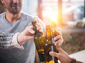 Gruppe Männer stößt mir Bierflaschen an.