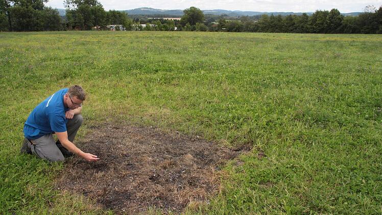 Noch immer findet Ralf Michel an der Absturzstelle Metall- und Plastikteile, die er aufsammelt, damit sie nicht ins Heu gelangen. Im Hintergrund, nur wenige Hundert Meter vom Unglücksort entfernt, ist das Anwesen von Ralf Michel zu sehen. Fotos: Jürgen Gärtner