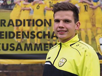 Julian Brönner vor der Plakatwand am Sportgelände des FC Thulba. Das Motto "Tradition. Leidenschaft. Zusammenhalt" passt natürlich bestens zum Kreissieger des Bayerischen Fußballverbands bei der "Aktion Junges Ehrenamt".Jürgen Schmitt