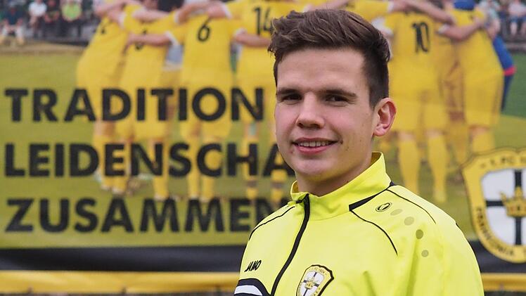 Julian Brönner vor der Plakatwand am Sportgelände des FC Thulba. Das Motto "Tradition. Leidenschaft. Zusammenhalt" passt natürlich bestens zum Kreissieger des Bayerischen Fußballverbands bei der "Aktion Junges Ehrenamt".Jürgen Schmitt