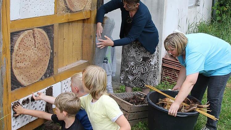 Niklas Keller, Elias Brettschneider, Paul Köhler, Vorsitzende Karin Rittweger und Zweite Vorsitzende Tanja Pohl (von links) nehmen die letzten Arbeiten am neuen Insektenhotel vor. Foto: Michael Stelzner