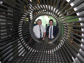 Schauen in die Röhre, die Brennholzstücke reinigt: Landrat Michael Busch und Dominic Dressel (rechts).1:87 Foto: Berthold Köhler