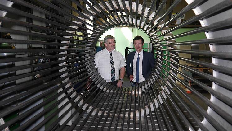 Schauen in die Röhre, die Brennholzstücke reinigt: Landrat Michael Busch und Dominic Dressel (rechts).1:87 Foto: Berthold Köhler