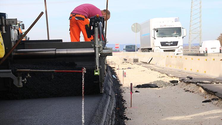 Die Arbeiter verlegen den neuen Asphalt während der Verkehr nebendran weiter läuft. Foto: Ronald Heck