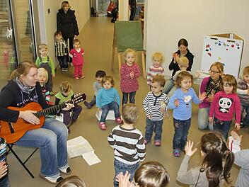 Mit Liedern begrüßten die älteren Kindergarten-Kinder die Neulinge in der Krippengruppe, die wegen eines Schnullers zum Teil gar nichtmitsingen konnten. Annika Schnaus spielte die Gitarre, die Erzieherinnen Claudia Hümmer und Julia Hartung stimmten mit ein.  Foto: Ralf Kestel