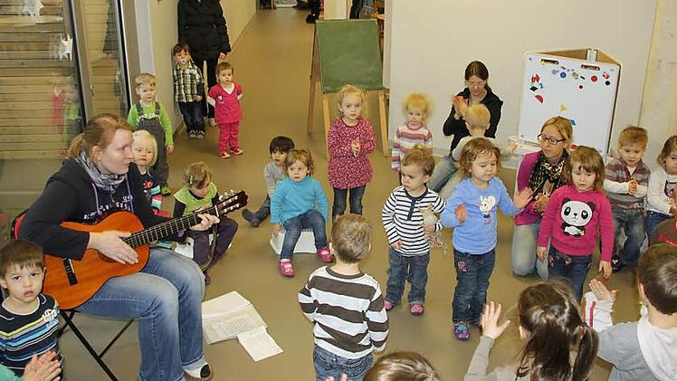 Mit Liedern begrüßten die älteren Kindergarten-Kinder die Neulinge in der Krippengruppe, die wegen eines Schnullers zum Teil gar nichtmitsingen konnten. Annika Schnaus spielte die Gitarre, die Erzieherinnen Claudia Hümmer und Julia Hartung stimmten mit ein.  Foto: Ralf Kestel