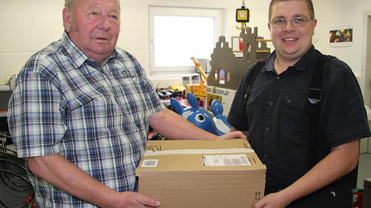 Gerhard Degelmann überrreicht eine Kiste Spielsachen seiner Enkel an Jörg Geyer von der Stadtsteinacher Feuerwehr. Foto: Sonja Adam