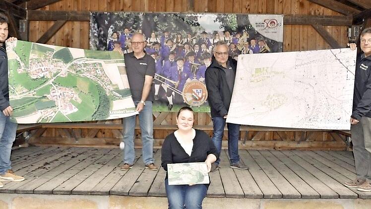 Zwei Karten von Kraisdorf - links eine Luftaufnahme vom vergangenen Jahr, rechts eine historische Vermessungskarte von 1849 - hat die Blasmusik Kraisdorf vom Vermessungsamt Schweinfurt erhalten. Die Karten halten (von links) Lukas Schönmann, Gerhard Eller, Josef Kneuer und Herbert Schönmann. Vorne sitzend zeigt Anna Bühler das Modell der Luftaufnahme aus dem 3D-Drucker.  Foto: Simon Albrecht