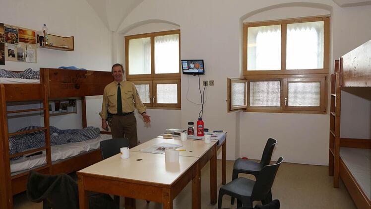 Georg Winkler steht in einer Sechs-Bett-Zelle im Barockbau mit den mehrfach gesicherten Fenstern zur Regnitz hin.