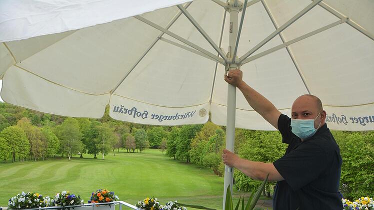 Darius Hancea spannt im Golfplatz-Café den Sonnenschirm auf.