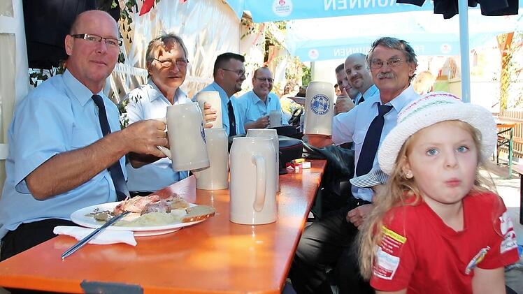 Die Höchstadter Feuerwehr stärkt sich nach dem Fahnenumzug. Die vierjährige Viviene (vorne) trug das Schild des Spielmannszugs.
