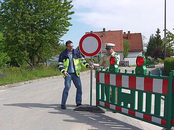 Neu justiert: Timo Sommerluksch und Ulrich Bosecker kennen diese Tätigkeit von vielen Baustellen - sie müssen die Absperrungen wieder so hinstellen, dass sie von den Verkehrsteilnehmern beachtet werden. In der Mährenhäuser Straße in Weidach werden die Schilder wohl bis Ende des Jahres stehenbleiben. Foto: Berthold Köhler