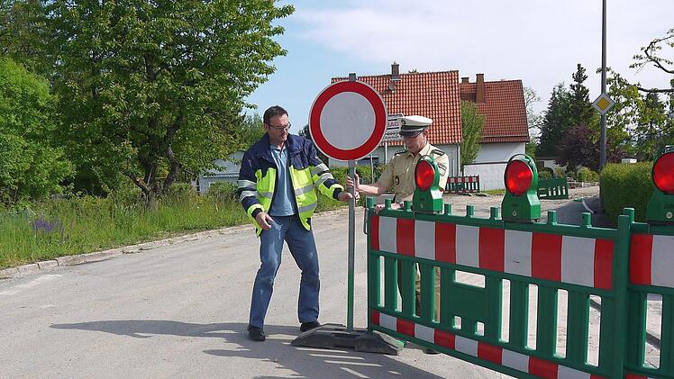 Neu justiert: Timo Sommerluksch und Ulrich Bosecker kennen diese Tätigkeit von vielen Baustellen - sie müssen die Absperrungen wieder so hinstellen, dass sie von den Verkehrsteilnehmern beachtet werden. In der Mährenhäuser Straße in Weidach werden die Schilder wohl bis Ende des Jahres stehenbleiben. Foto: Berthold Köhler