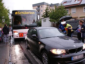 Elterntaxi gegen Schulbus: Der dunkle BMW blockiert die Haltestelle, Polizist Florian Heuring konfrontiert den Fahrer, Journalisten begleiten das Ganze.