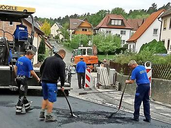 Zwischen den beiden Fotos liegen nur wenige Wochen. Die Straßenarbeiter trafen letzte manuelle Vorbereitungen für die abschließende Feinteerschicht in der Bieberbacher Straße. Der Straßenfertiger stand schon bereit.  Fotos: Klaus Oelzner