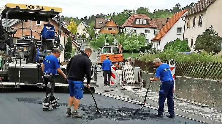 Zwischen den beiden Fotos liegen nur wenige Wochen. Die Straßenarbeiter trafen letzte manuelle Vorbereitungen für die abschließende Feinteerschicht in der Bieberbacher Straße. Der Straßenfertiger stand schon bereit.  Fotos: Klaus Oelzner