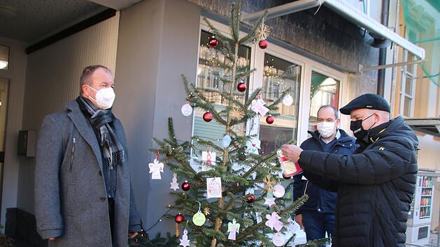 Alexander Schmidt (2.v.r.) hat den Wunschbaum vor dem OBA-B&uuml;ro aufgestellt. Rainer Waldvogel (links) brachte noch einen ganzen Stapel Wunschzettel aus Maria Bildhausen mit. Michael Kastl nahm gleich einen Zettel ab und wird nun einen Wunsch erf&uuml;llen. Thomas Malz