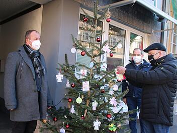 Alexander Schmidt (2.v.r.) hat den Wunschbaum vor dem OBA-Büro aufgestellt. Rainer Waldvogel (links) brachte noch einen ganzen Stapel Wunschzettel aus Maria Bildhausen mit. Michael Kastl nahm gleich einen Zettel ab und wird nun einen Wunsch erfüllen. Thomas Malz
