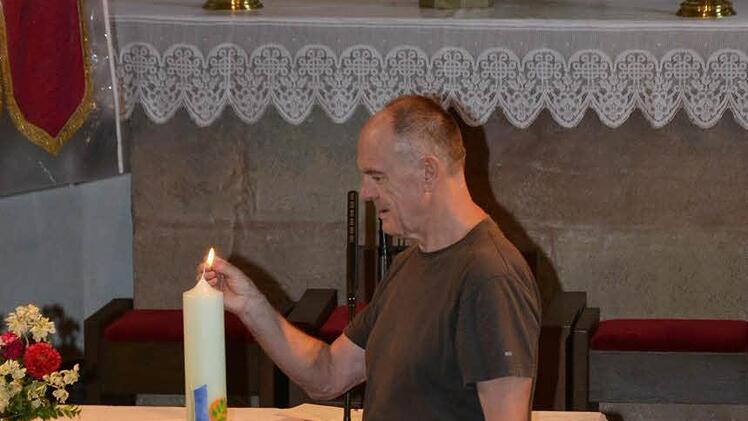 Präses Tadeusz Falkowski zündet die Kerze in der Aschacher Kirche an und betete mit den Wallfahrern.