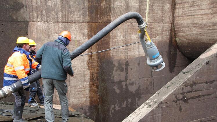 Bauleiter Jörg Blömer (rechts) und zwei Mitarbeiter bringen eine Pumpe in Position, die Restwasser im Bereich der Tore entfernen soll.  Foto: Andreas Schmitt