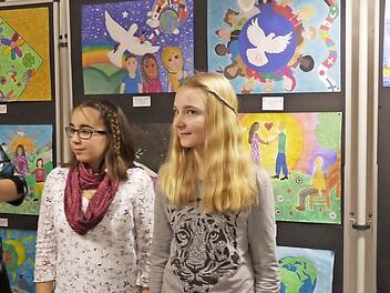 Kerstin Engel erklärt mit Paula Popov, Alia Staub und Armin Wachter die Bildideen der Kinder. Postkarten mit den Motiven kann man während der Ausstellung in der Bank und beim Stand des Clubs am 28. und 29. November vor Foto Brinke kaufen. Der Erlös geht an Integrationsklassen in Forchheim und ans internationale Lionsprojekt Sight First Foto: Pauline Lindner