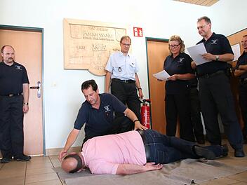 Kann der Feuerwehranwärter eine Person in die stabile Seitenlage versetzen? Die Ausbilder simulieren eine typische Prüfungssituation. Jürgen Schemmel (helles Hemd) von der Feuerwehrschule Würzburg informierte in der Kissinger Feuerwache über die neue "Modularisierte Truppausbildung". Foto: Ronald Heck