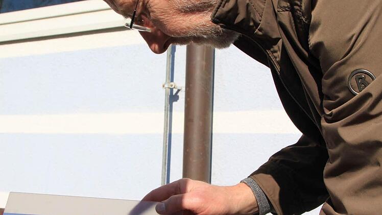 Alfred Förner justiert die Tafel, auf der die Sonnenscheibe und der Schatten des sich davorschiebenden Mondes zu sehen sind.