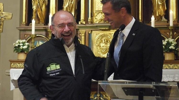 Bürgermeister Ludwig Wahl (rechts) überreichte Pfarrer Joan Vinyeta Puntí zum Abschied eine Röttenbach-Jacke mit Namenszug. Foto: Pauline Lindner