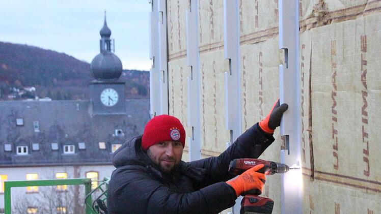 Von einer Hebebühne aus montiert ein Arbeiter die Stahlkonstruktion für die Fassadenverschalung. Foto: Benedikt Borst