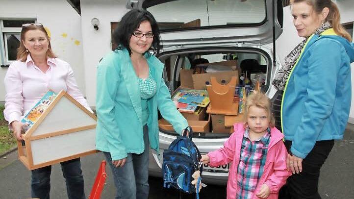 Spende für Flüchtlinge: Susanne Wicht (2.v.l.) und Kindergartenleiterin Juliane Schneider (links) beladen das Auto mit Spielsachen aus dem Kindergarten Willersdorf. Die kleine Emily hilft mit, sie packt einen kleinen Kinderrucksack mit Teddybär ins Auto.  Foto: Mathias Erlwein