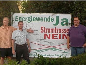 In Schondra, am Ortseingang an der Kissinger Straße, steht eines der Banner, das (von links) BI-Vorsitzender Reiner Morshäuser (Singenrain), stellvertretender Vorsitzender Jochen Knüttel (Schildeck) und Bürgermeister Bernold Martin präsentieren. Foto: Oswald Türbl