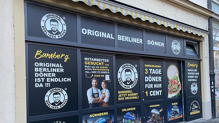 Ladenfassade von "Original Berliner Döner" in Bamberg. Werbung: Döner für 1 Cent (3 Tage). Schriftzüge und Grafiken zu Qualität und internationalen Filialen.