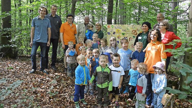 Die beteiligten Kinder und ihre Betreuer sowie sowie B&uuml;rgermeister Klaus Homann (Zweiter von rechts) und stellvertretender Landrat Johann Pfister (hinten, Vierter von links) bei der Er&ouml;ffnung des Wald-Kinder-Kunst-Weges im Wald n&ouml;rdlich von Erlach Foto: Annette Sch&auml;fer
