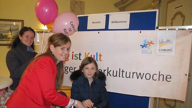 Bianca Haischberger befestigt ein Freundschaftsband am Arm von Franziska R. Mit auf dem Bild ist Stephanie R., Franziskas Mutter. Foto: Martin Koch