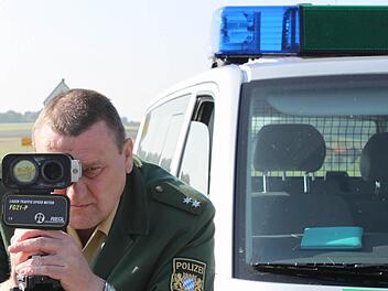 Sebastian Selig von der Höchstadter Polizei visiert mit der Laserpistole Autos an. In Röttenbach soll zunächst mit Pflanztrögen und aufgemalten Parkbuchten das Fahrverhalten getestet werden. Foto: Andreas Dorsch (Archiv)