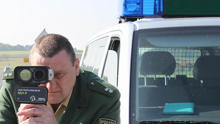 Sebastian Selig von der Höchstadter Polizei visiert mit der Laserpistole Autos an. In Röttenbach soll zunächst mit Pflanztrögen und aufgemalten Parkbuchten das Fahrverhalten getestet werden. Foto: Andreas Dorsch (Archiv)